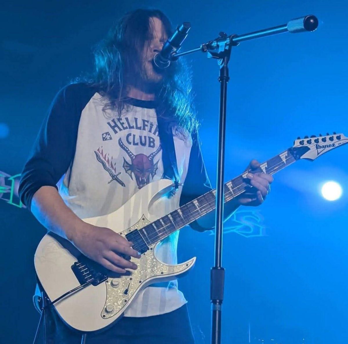 Caden84 live on stage with a white Ibanez guitar